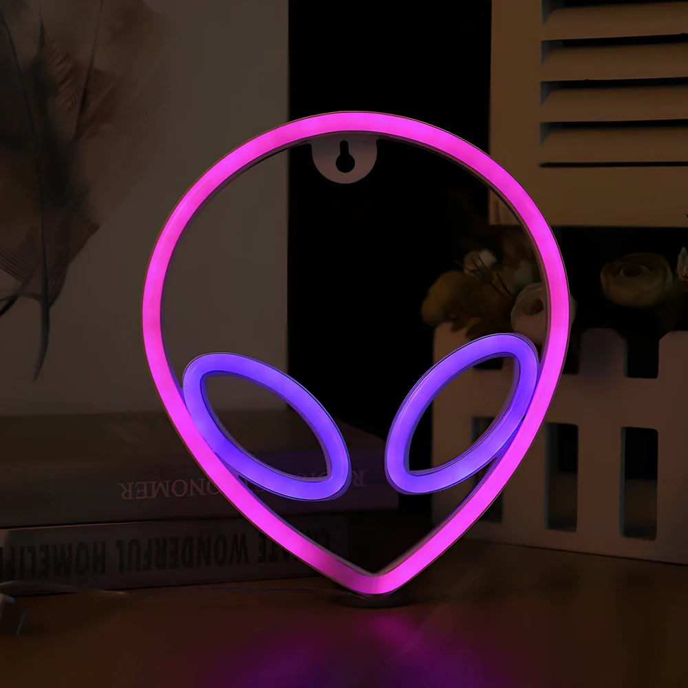 LED wall hanging neon modelling light with alien face design showing pink eyes and blue background illumination