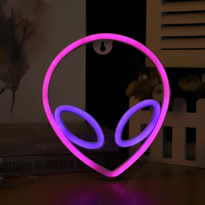 LED wall hanging neon modelling light with alien face design showing pink eyes and blue background illumination