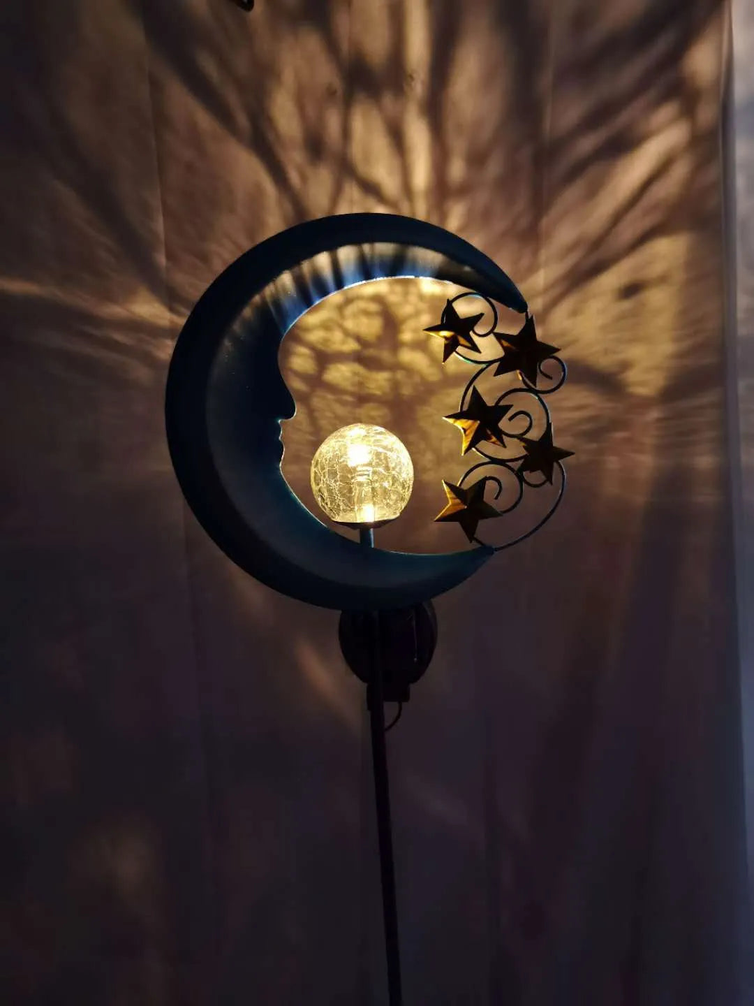 Blue hollow moon-shaped solar garden light with wrought iron frame and crackled glass ball.