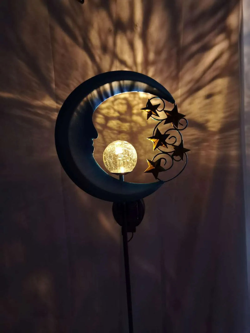 Solar powered decorative light shaped as a hollow wrought iron blue moon with LED light source, featuring a moon crack glass ball design and an IP65 protection rating for outdoor use in gardens, lawns, and as a pathway light.