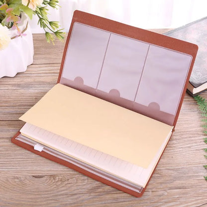 Leather cover business notebook with strap binding, open on warm brown acid-free paper.