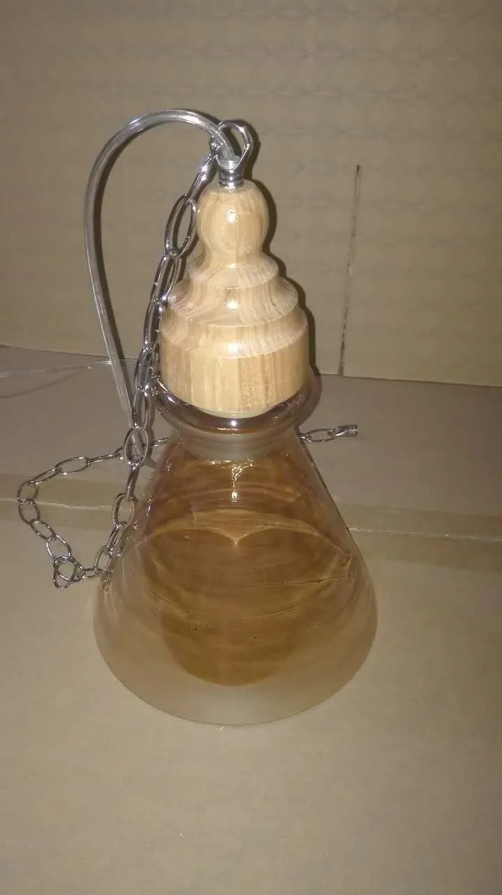 Glass single head pendant light with wood grain finish and adjustable cord.
