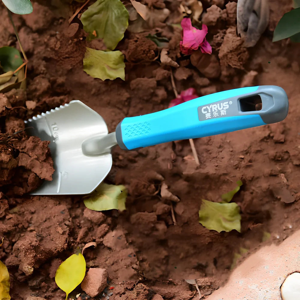 Aluminium garden tool set with cast shovel, three-claw harrow, and reinforced gardening gloves on soil