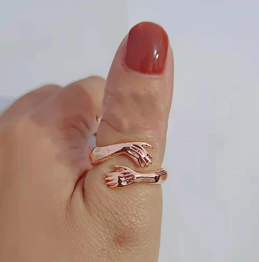 Adjustable geometric love hands embracing ring in gold and silver, perfect for gifts.