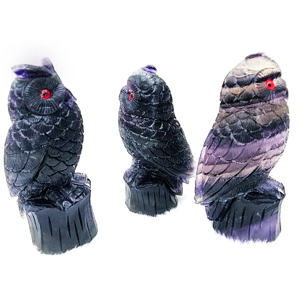 Hand-carved purple fluorite stone owl ornament on a neutral background, showing detailed carving.