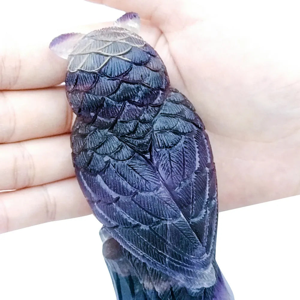 Hand-carved purple fluorite stone owl ornament on a neutral background, showing detailed carving.