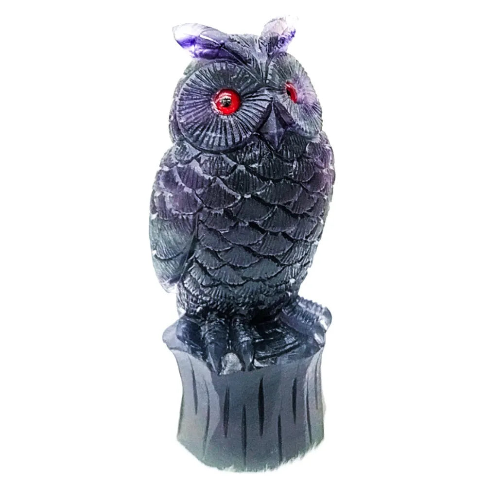 Hand-carved purple fluorite stone owl ornament on a neutral background, showing detailed carving.