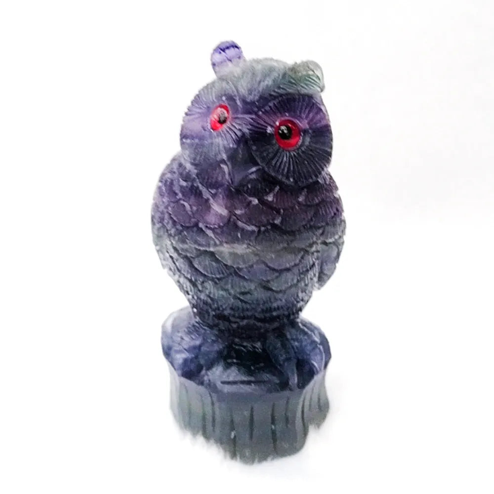 Hand-carved purple fluorite stone owl ornament on a neutral background, showing detailed carving.