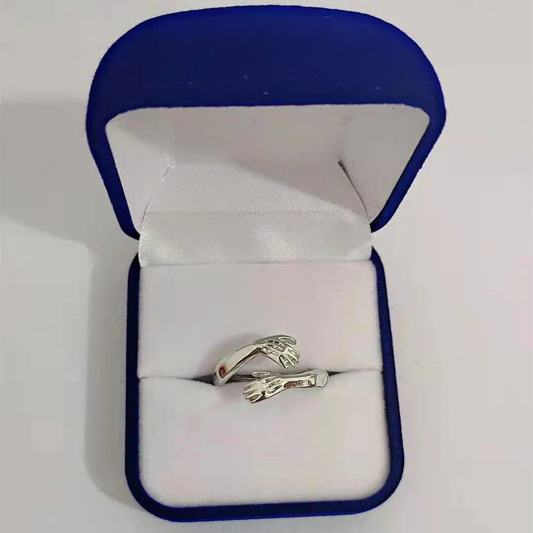 Adjustable geometric love hands embracing ring in gold and silver, perfect for gifts.