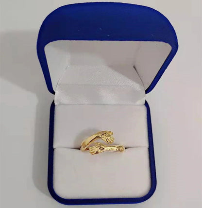 Adjustable geometric love hands embracing ring in gold and silver, perfect for gifts.