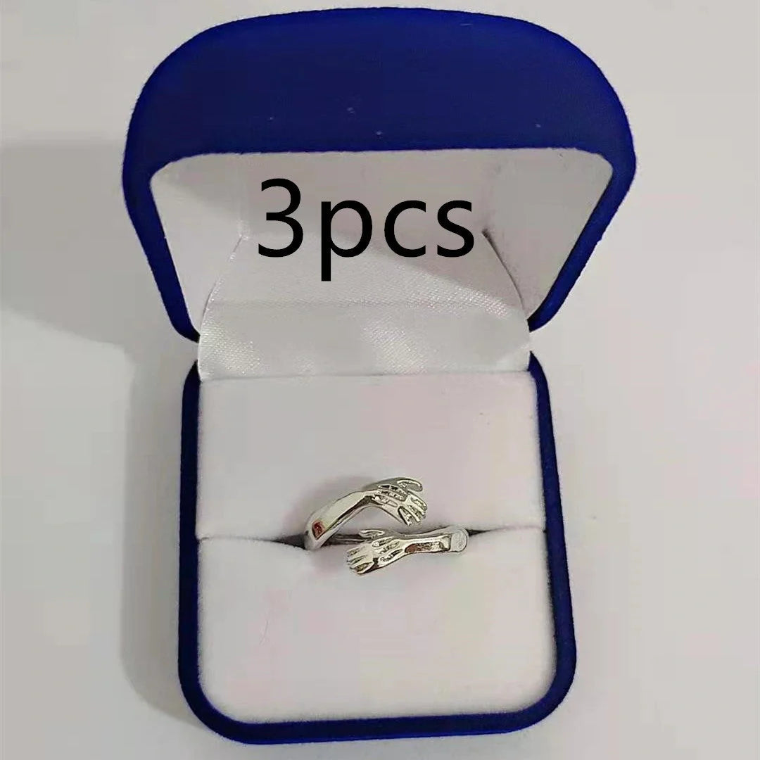 Adjustable geometric love hands embracing ring in gold and silver, perfect for gifts.