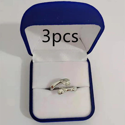 Adjustable geometric love hands embracing ring in gold and silver, perfect for gifts.