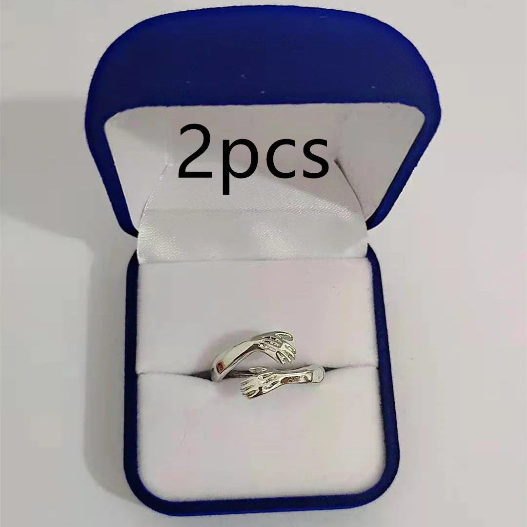 Adjustable geometric love hands embracing ring in gold and silver, perfect for gifts.