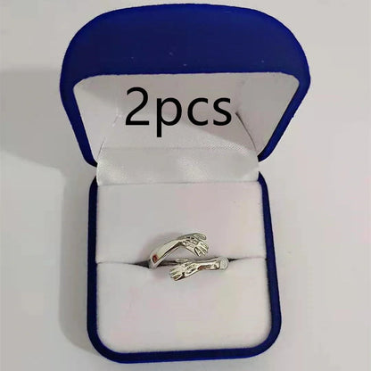 Adjustable geometric love hands embracing ring in gold and silver, perfect for gifts.