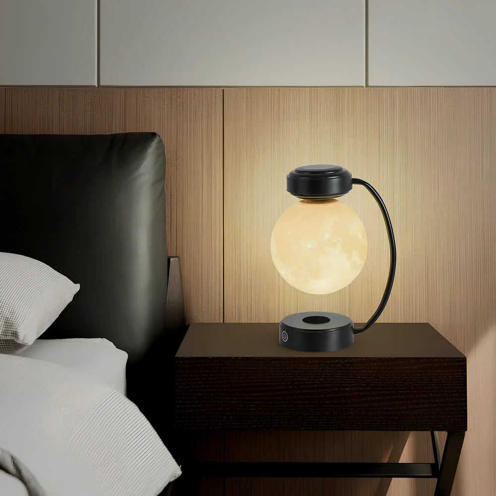 Black magnetic levitation moon lamp floating above base with golden illumination, showing touch control area