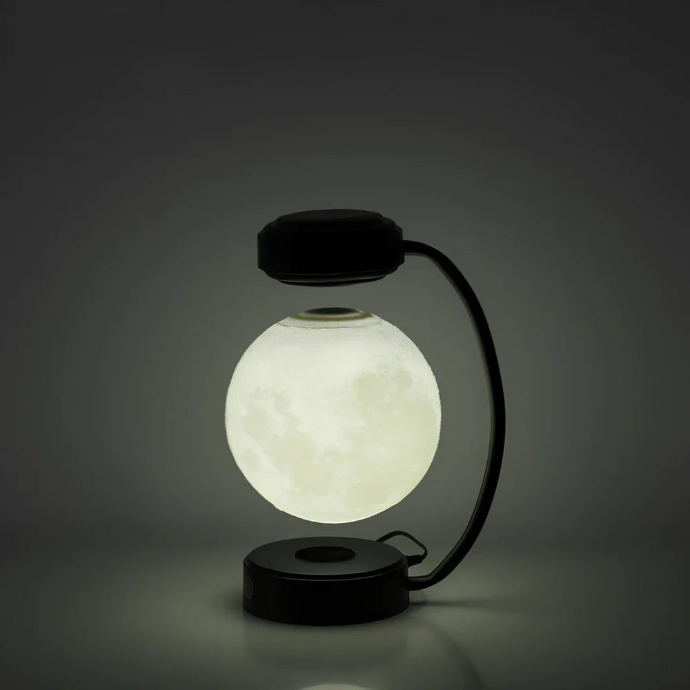 Black magnetic levitation moon lamp floating above base with golden illumination, showing touch control area