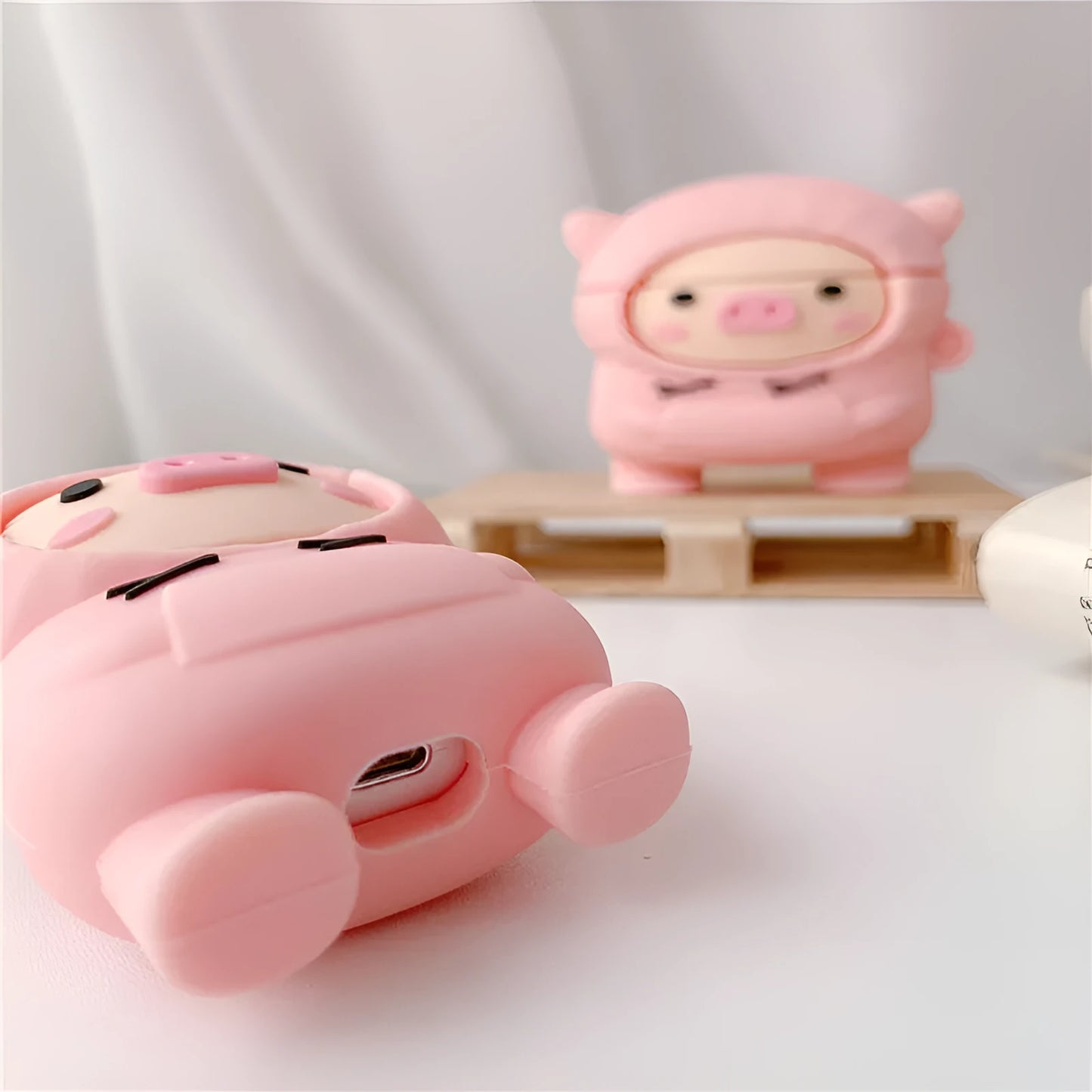 Pink silicone pig earphone case with flip lid and carabiner hook for Apple AirPods.