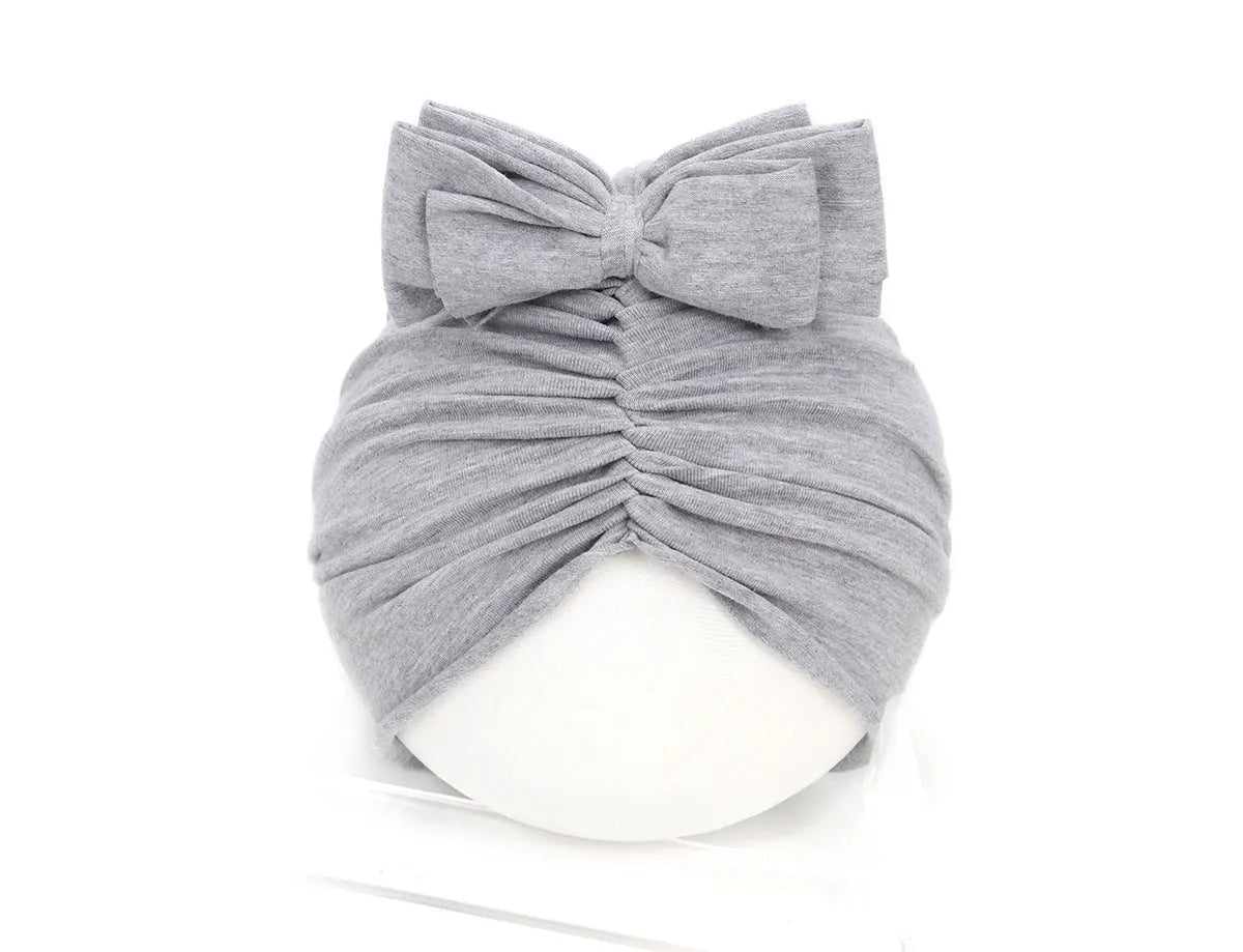 Soft acrylic knitted baby cap for newborns and toddlers in a solid colour, showing stretch fit.
