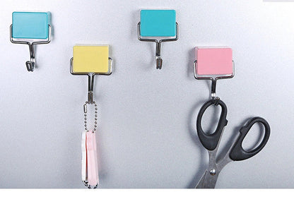 Yellow magnetic plastic hook with 4cm diameter base on metal surface holding kitchen utensils