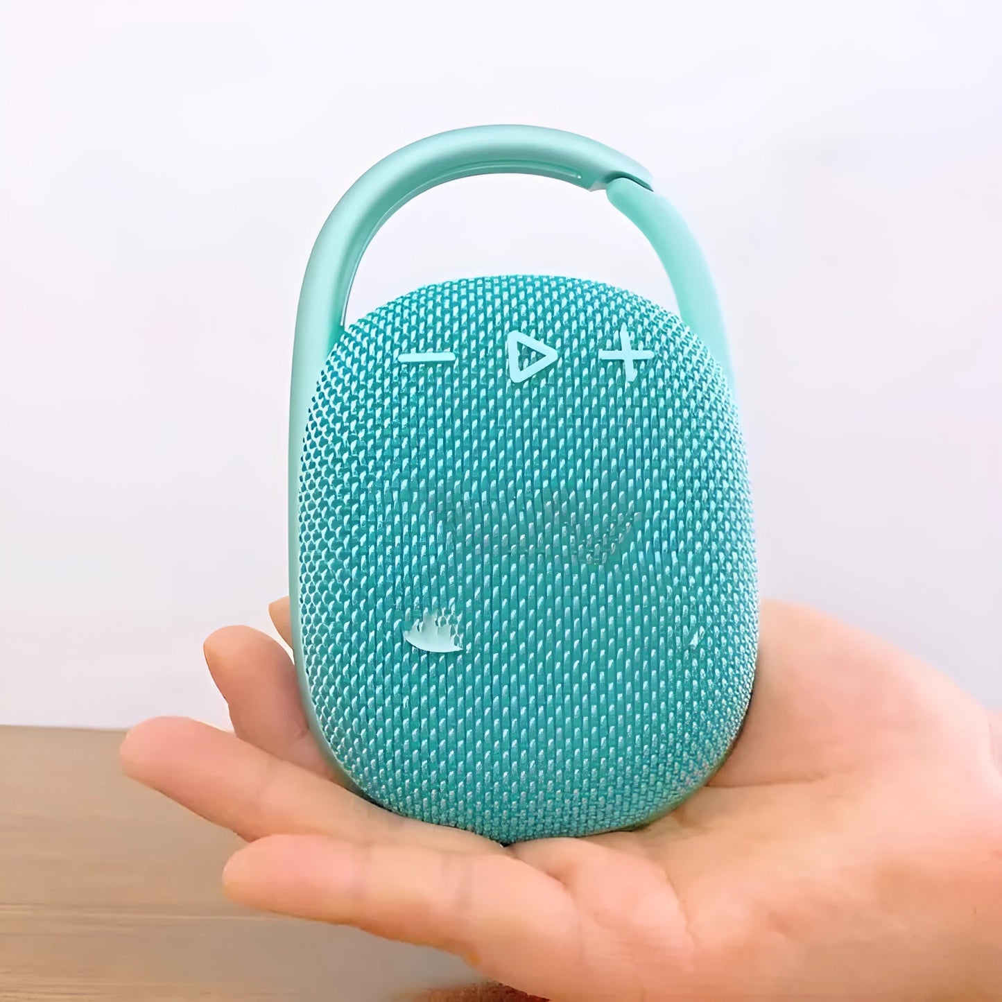 Compact pink 4th generation portable Bluetooth speaker with USB charging cable on a wooden table.