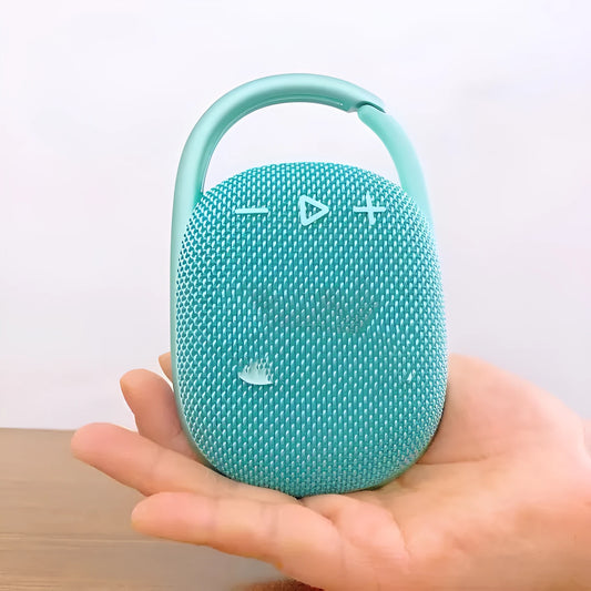Compact pink 4th generation portable Bluetooth speaker with USB charging cable on a wooden table.