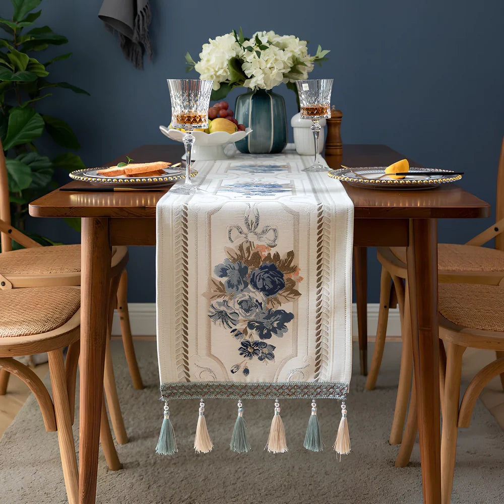 White chenille table runner with long tassels on wooden dining table