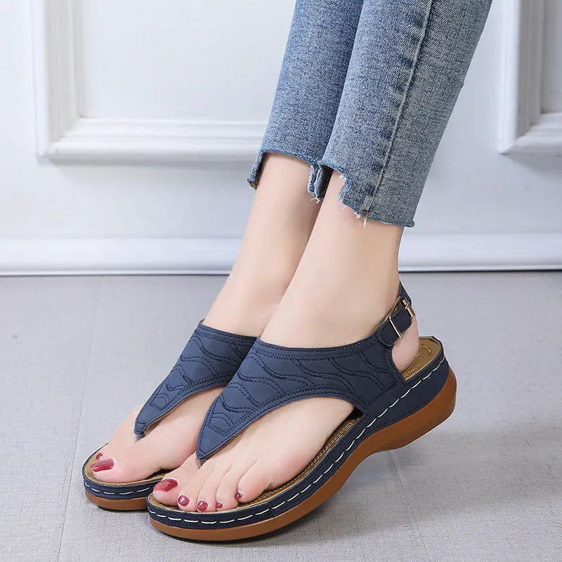 Women's wedge heel flip flop sandals in black with adjustable back strap on a light background