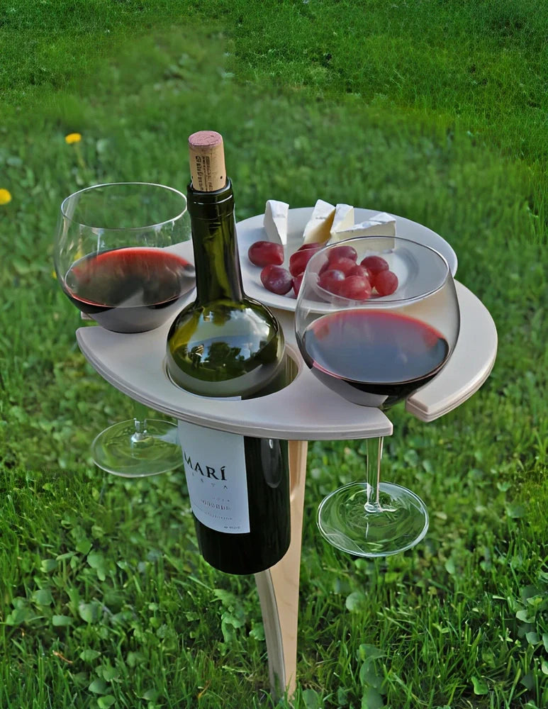 Wooden folding wine table with ground stakes holding wine bottle and glasses outdoors