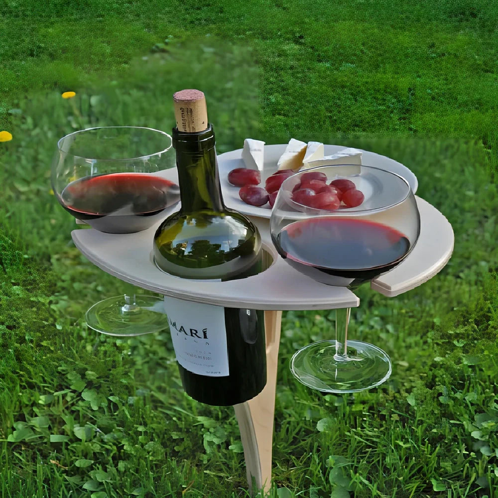 Wooden folding wine table with ground stakes holding wine bottle and glasses outdoors