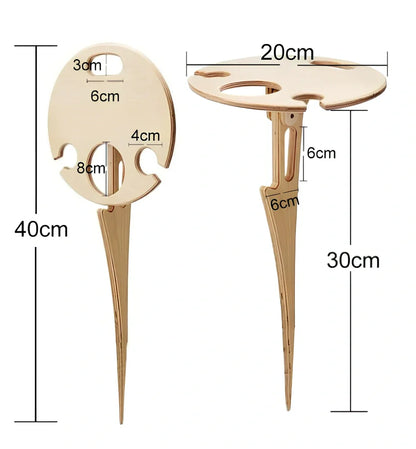 Wooden folding wine table with ground stakes holding wine bottle and glasses outdoors