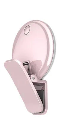 Round black mobile phone fill light with adjustable clip attached to a smartphone.