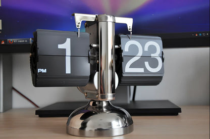 Black and white flip digital clock showing 12:34 with retro flip digits on wooden table