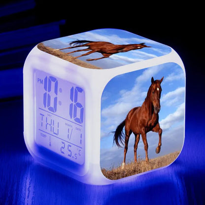Square creative alarm clock showing LED time display, thermometer reading, and colour-changing design on bedside table