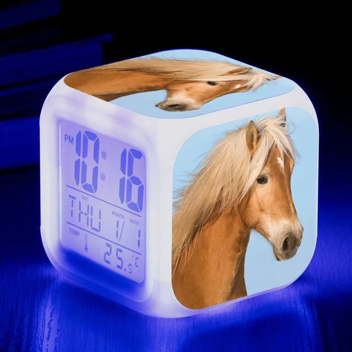 Square creative alarm clock showing LED time display, thermometer reading, and colour-changing design on bedside table