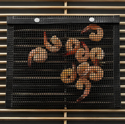 Black grill mesh bag with non-stick grid mat on barbecue, showing smoke circulation through mesh design