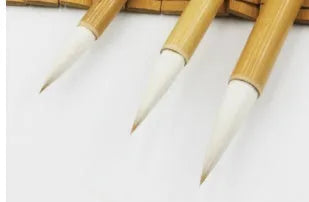 Three traditional Chinese writing brushes with woolen bristles and bamboo handles in large, medium, small sizes