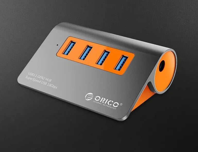 Dark grey aluminium USB-C laptop docking station with orange accents, showing USB ports, HDMI, and card readers.