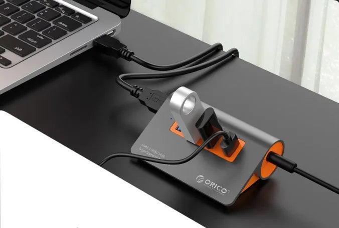 Dark grey aluminium USB-C laptop docking station with orange accents, showing USB ports, HDMI, and card readers.