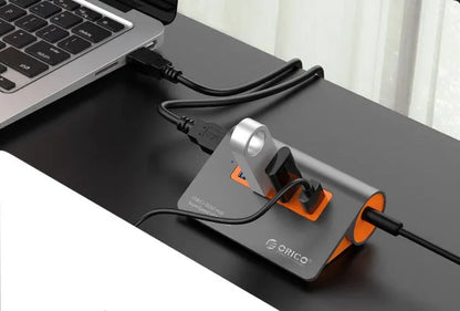 Dark grey aluminium USB-C laptop docking station with orange accents, showing USB ports, HDMI, and card readers.