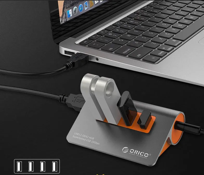 Dark grey aluminium USB-C laptop docking station with orange accents, showing USB ports, HDMI, and card readers.