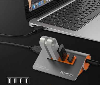 Dark grey aluminium USB-C laptop docking station with orange accents, showing USB ports, HDMI, and card readers.
