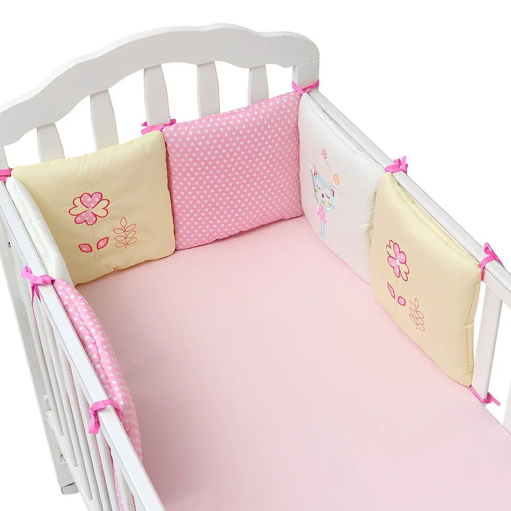 Six 30cm square cotton baby bedding panels with animal patterns surrounding white cot