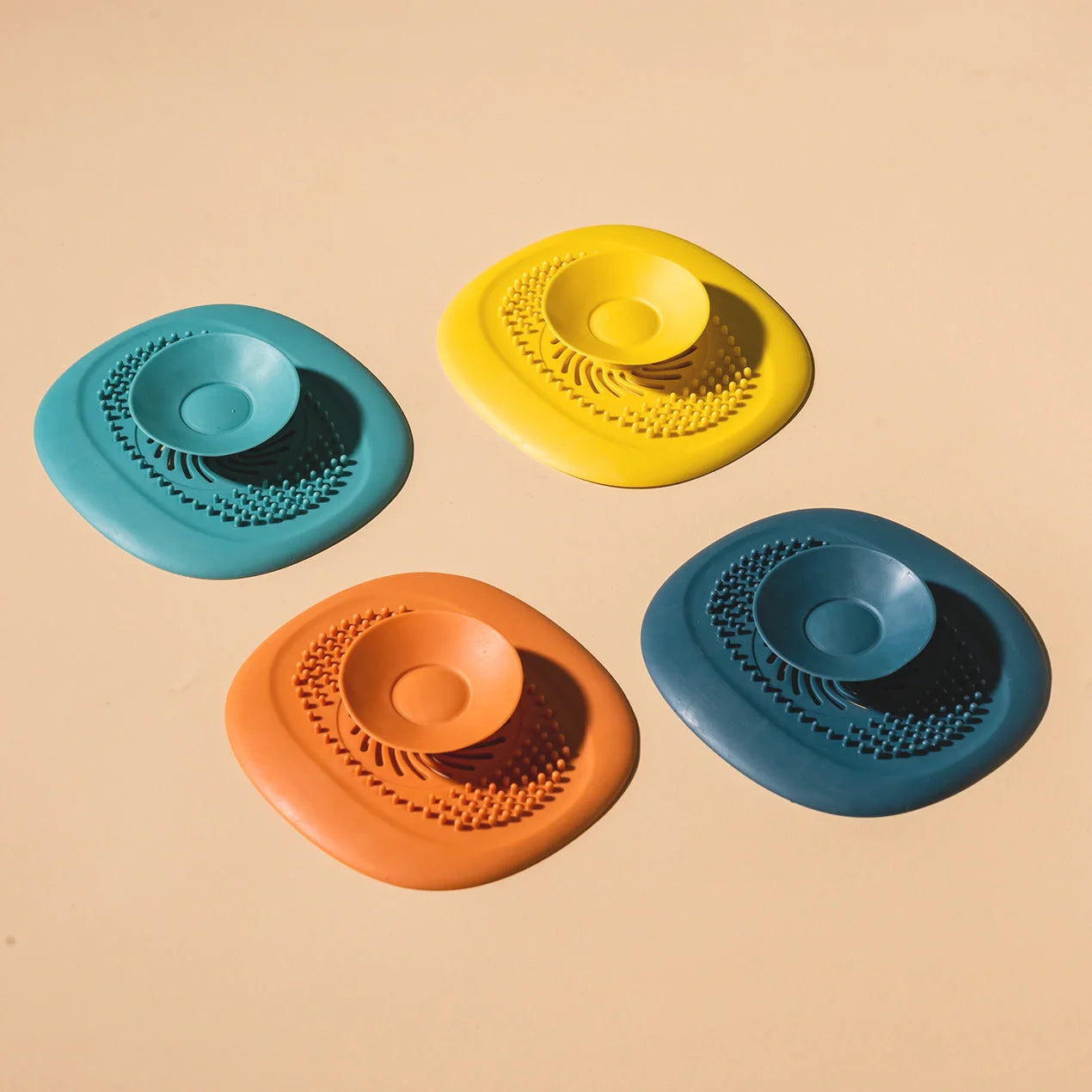 TPR vortex design sink drain cover in twilight orange, quiet blue, mango yellow, and gentian green