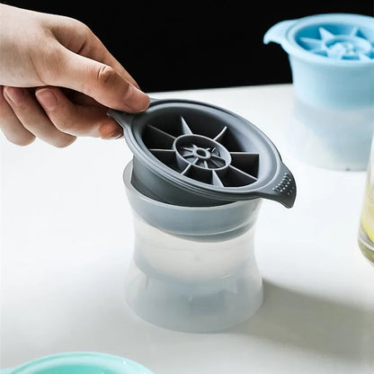 Silicone ice tray in various colours making large ice cubes, including hockey puck and geometric shapes, on a kitchen counter