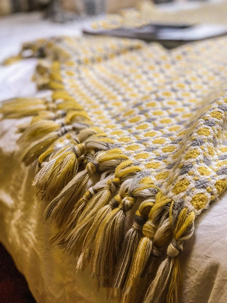 Yellow geometric pattern blanket measuring 130cm by 152cm with tassel edges