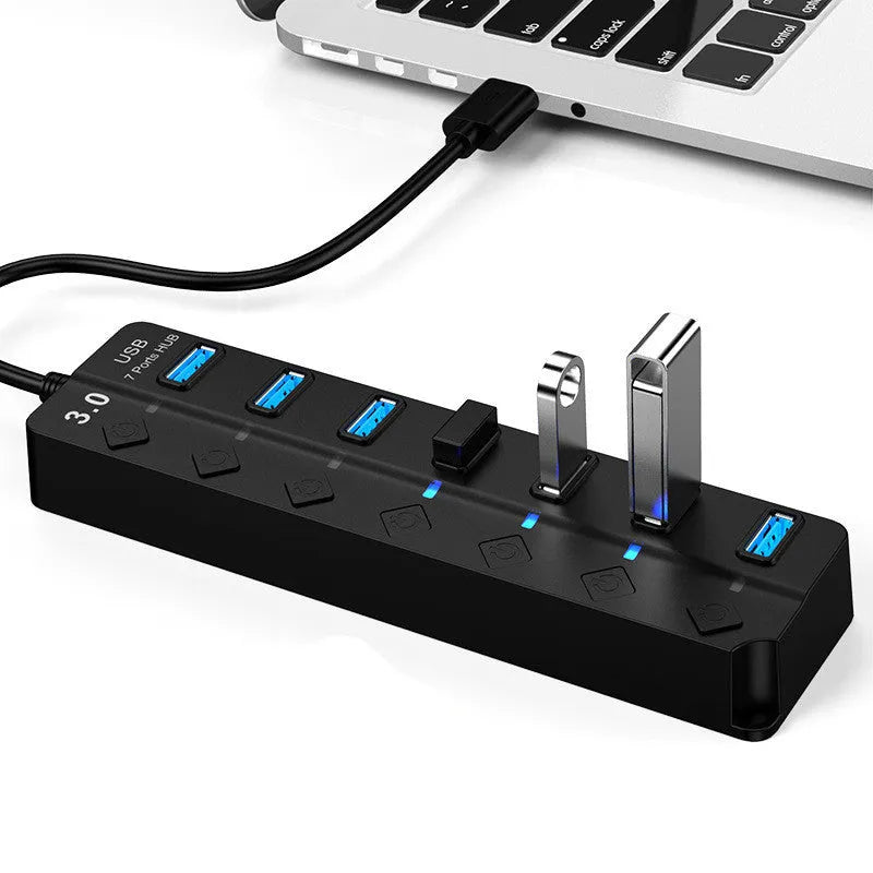 Black 7-port USB 3.0 hub with external power adapter on desktop