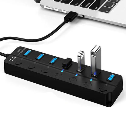 Black 7-port USB 3.0 hub with external power adapter on desktop