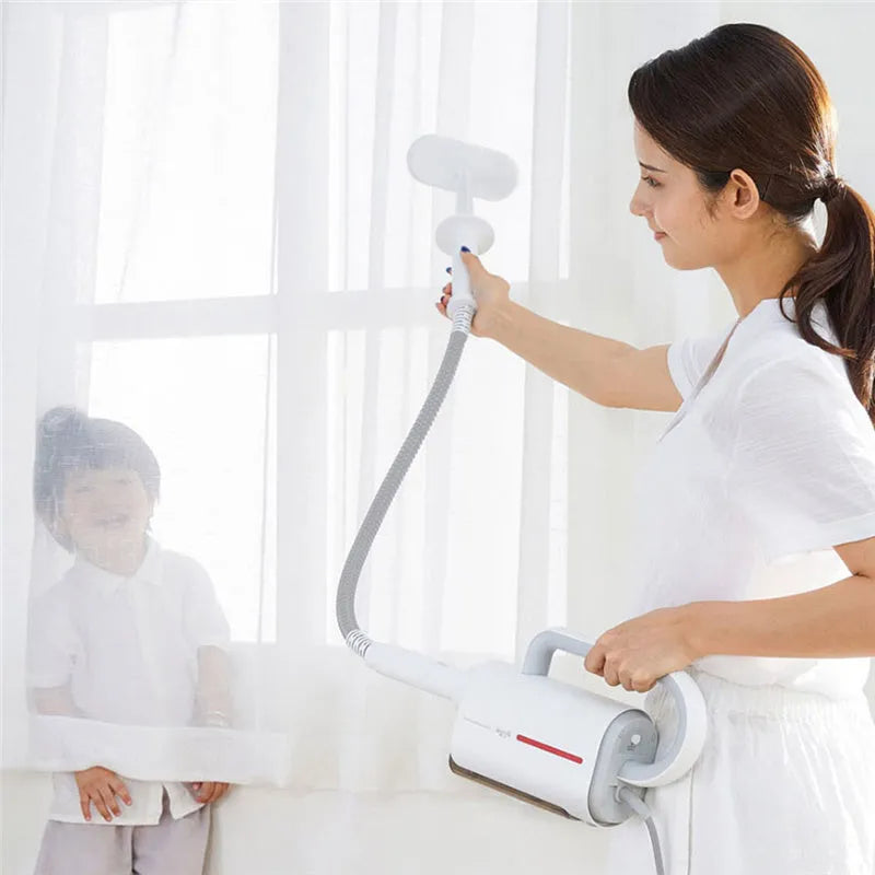 White Deerma handheld steam cleaner with multiple brush heads and extension tubes on a table