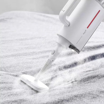 White Deerma handheld steam cleaner with multiple brush heads and extension tubes on a table