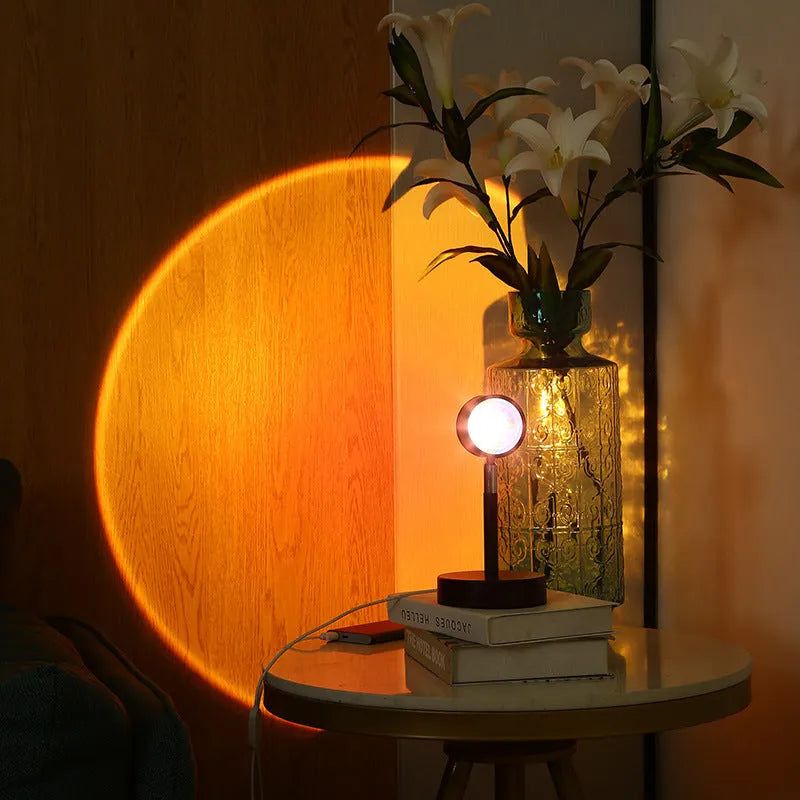 Black USB dual-head sunset rainbow projection lamp with touch controls on bedside table